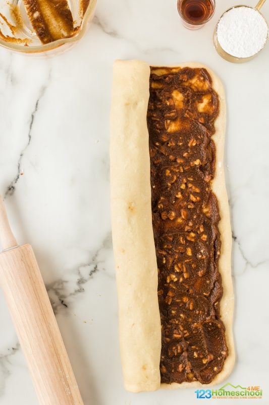 Begin by taking the long 18″ edge of the dough and roll it towards you to create a long, tube-shaped roll. 