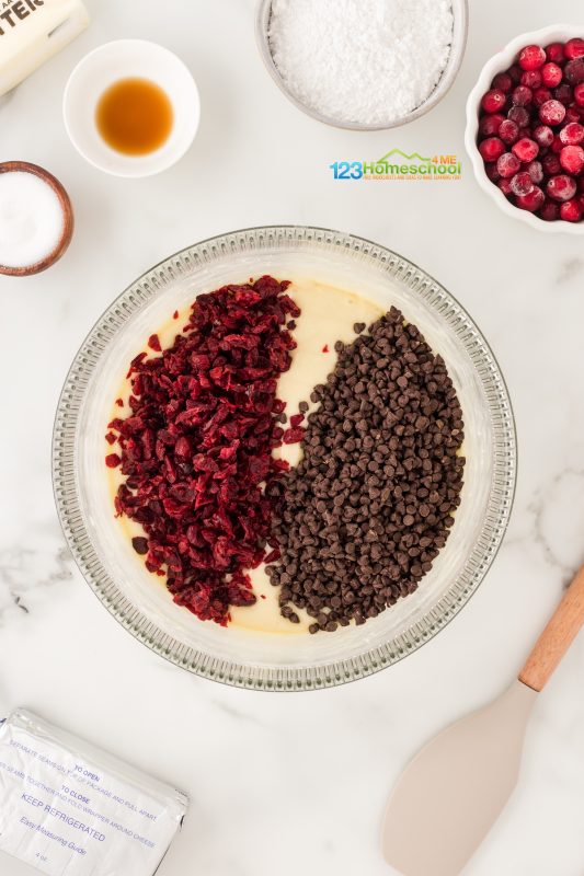 add dried cranberries and chocolate chips to white chocolate cake Mix together a yellow cake mix using the package instructions! For mine I added 3 eggs, 1/2 cup of canola oil, and 1 cup of water. Now gently fold in chopped cranberries and mini chocolate chips.