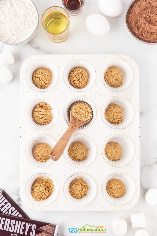 graham cracker cupcakes Let's start with the prep work:
Preheat your oven to 350°F.
Line your cupcake pans with 24 cupcake liners.
Crush graham crackers until you get 1 3/4 cup of crumbs! You can use a food processor or simply place them in a sturdy Ziploc bag and crush them with a mallet or rolling pin until they’re fine crumbs.
In a small bowl, combine the graham cracker crumbs with 3 Tablespoons sugar and 4 Tablespoons melted butter until it’s all well mixed.
Add 1 tablespoon of this mixture into each cupcake liner. Use the back of a spoon or a small cup to press it firmly into the bottom.