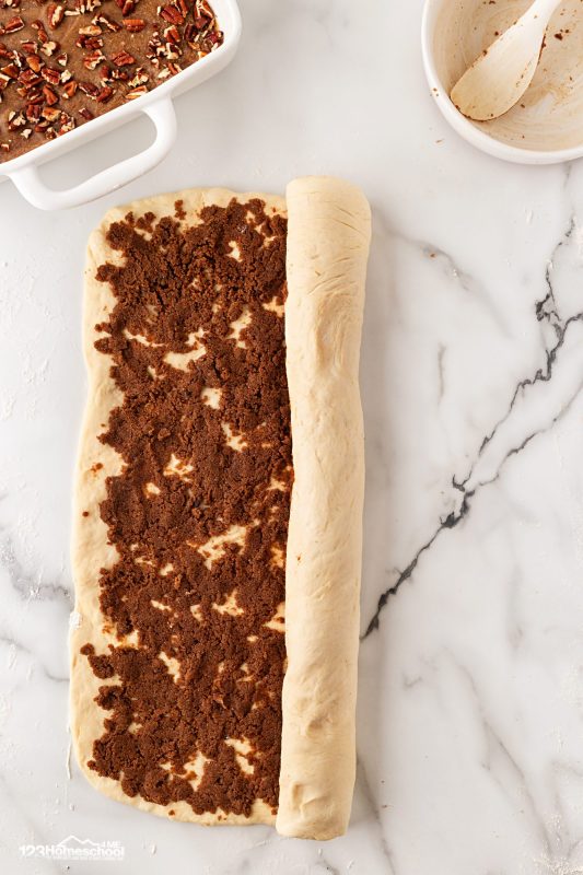 roll up dough with cinnamon mixture in the middle Then, roll the dough up lengthwise and pinch the seam to seal.